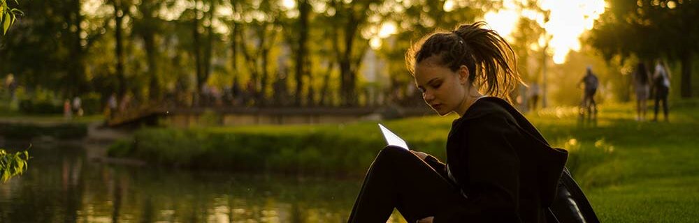 Girl studying by a pond