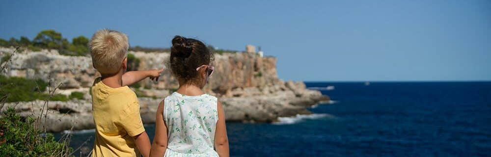 Two kids looking out at the ocean from a cliff top